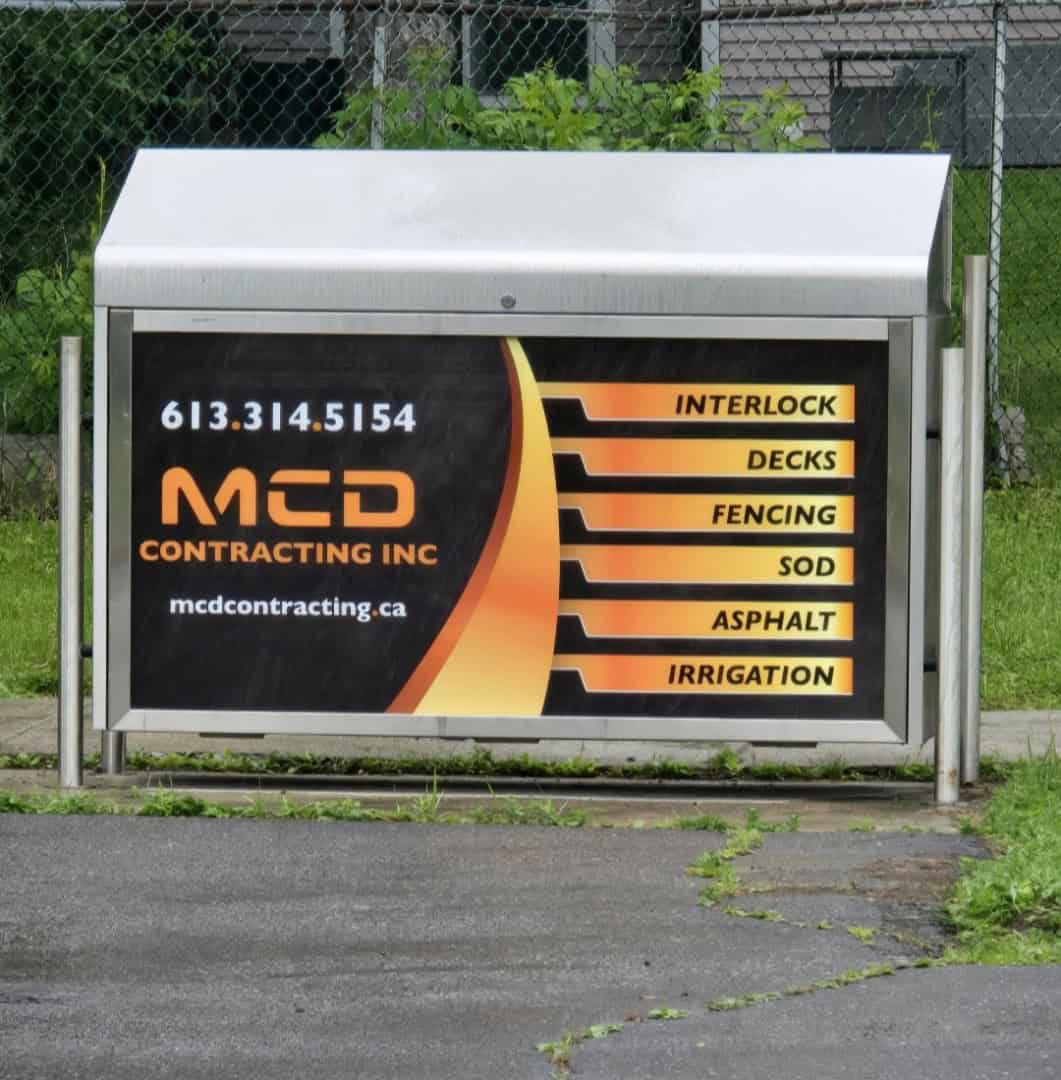 MCD Contracting service sign displays the company logo, contact info, and six key services: Interlock, Decks, Fencing, Sod, Asphalt, and Irrigation.
