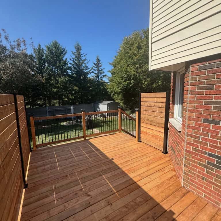 Interlocking paver walkway in varied tan and brown shades, bordered by dark stone, leading from a grassy area toward house steps and plants.