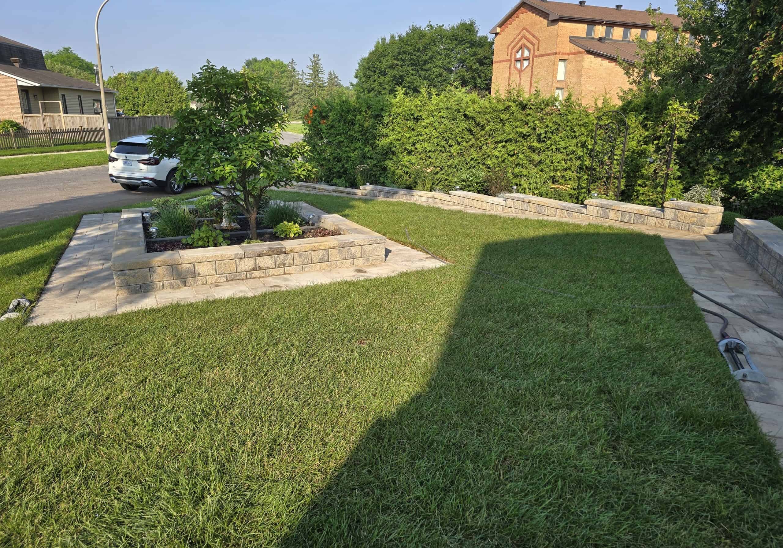 Raised stone planter retaining wall This photo features a raised stone planter and retaining walls bordering a lawn. Excellent example of front yard hardscaping and landscape design.